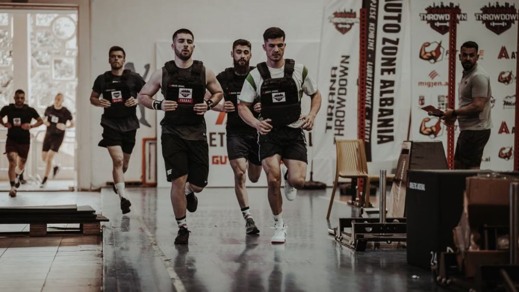 Group of men running in an indoor fitness competition, showcasing athleticism and determination.