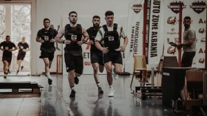 Group of men running in an indoor fitness competition, showcasing athleticism and determination.
